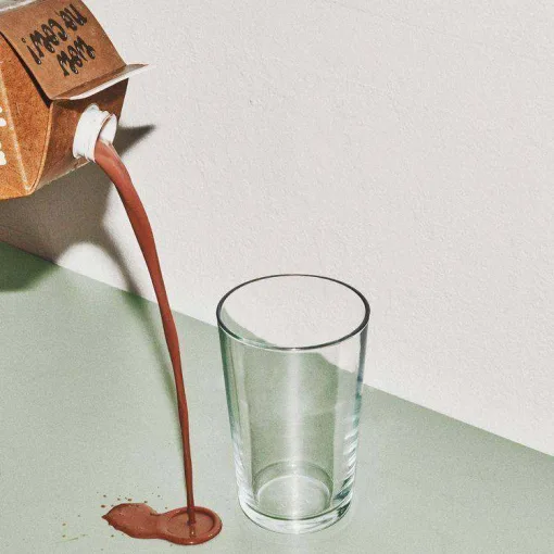 Ilustración de un tetrabrik derramando líquido marrón fuera de un vaso